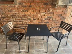 a black table and two chairs in front of a brick wall at Short Term Rental Re-imagined in Johannesburg