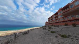 a building on a beach next to the ocean at Costa Calma / Playa Paraiso Laguna Blu in Costa Calma