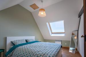 a bedroom with a bed with a blue comforter and a window at Superbe maison avec piscine et jacuzzi dans les dunes in Ambleteuse