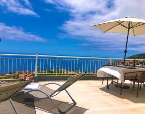 einen Tisch und Stühle auf einem Balkon mit Sonnenschirm in der Unterkunft Casa Neves three bedrooms and fantastic sea view in Arco da Calheta