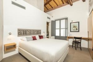 een witte slaapkamer met een bed en een bureau bij Domu Qirat - Authentic Rooms & Terraces in Tortolì
