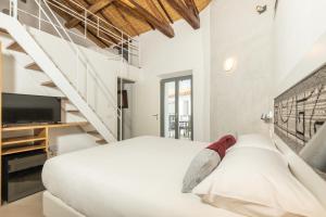 een witte slaapkamer met een groot bed en een trap bij Domu Qirat - Authentic Rooms & Terraces in Tortolì