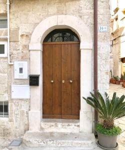 uma porta de madeira num edifício de pedra com um vaso de plantas em WePuglia - Casa di Mario em Monopoli