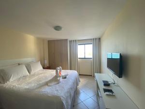 a hotel room with a bed and a flat screen tv at Natal Plaza 604-Ponta Negra in Natal