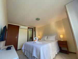 a bedroom with a bed with a white bedspread at Natal Plaza 604-Ponta Negra in Natal