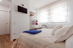 a white bedroom with a large bed with a blue pillow at Residenza 1955 in Matera