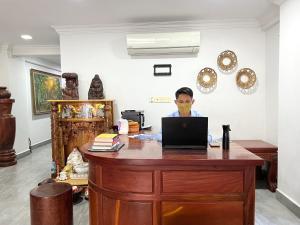a man sitting at a desk with a laptop computer at WH Bassac Residence in Phnom Penh