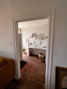 a hallway with a bathroom with a sink and mirror at Les Roches in Comprégnac