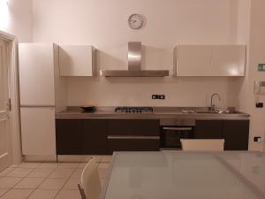 una cocina con armarios blancos y un reloj en la pared en Casa Alberoni, en Rávena