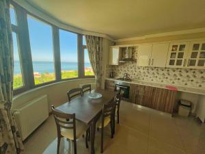 a kitchen with a table and chairs and windows at LUSTRA GARDEN SUİTE in Trabzon
