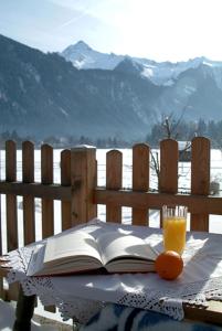 an open book on a table with a glass of orange juice at Landhaus Stefanie in Mayrhofen