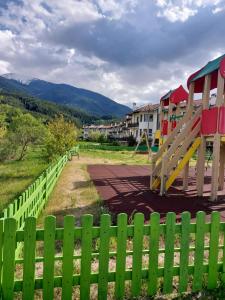 a green fence next to a playground with a slide at Pinerose Resort in Bansko