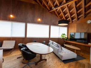 een kamer met een tafel, een bank en een tv bij SUMITSUGU HOUSE Atelier Suite in Kumamoto
