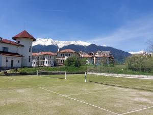 una pista de tenis con montañas al fondo en Pinerose Resort en Bansko