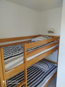 2 lits superposés avec des draps rayés bleus et blancs dans l'établissement Location appartement meublé bord de mer, à Fouesnant