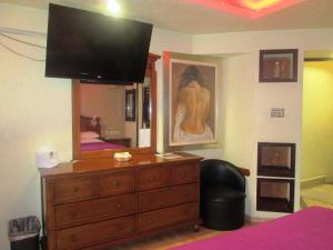 a bedroom with a dresser with a television on top of it at Hotel Real Azteca in Mexico City