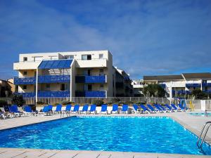 basen z krzesłami i budynek w obiekcie Appartement COSY avec piscine, accès direct plage w mieście Lacanau-Océan