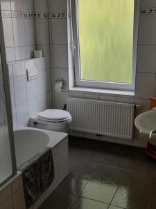 łazienka z toaletą, wanną i oknem w obiekcie FeWo Baltrum in Roggenstede w mieście Dornum