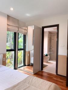 1 dormitorio con espejo grande y baño en The Title Rawai: Beachfront condotel en Rawai Beach