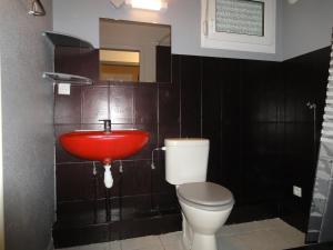 La salle de bains est pourvue d'un lavabo rouge et de toilettes. dans l'établissement Apollon home Robertsau, à Strasbourg