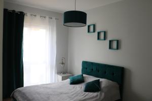 1 dormitorio con 1 cama con cabecero verde y ventana en Turkusowa Liwia, en Pogorzelica