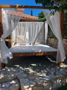a bed with mosquito netting on a stone patio at Villa Aquarius in Čilipi