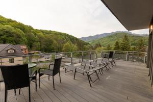 a deck with tables and chairs and a view of the mountains at Hotel Bloom in Caciulata