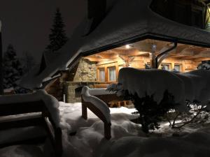una cabaña de madera cubierta de nieve por la noche en Domek Krupówki z widokiem na Giewont, en Zakopane