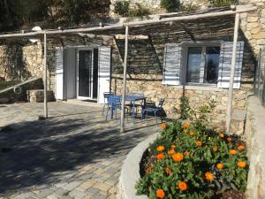 una casa in pietra con tavolo, sedie e fiori di Belvedere20guesthouse a Finale Ligure