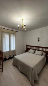 a bedroom with a large bed and a chandelier at El Palaero in La Alberca
