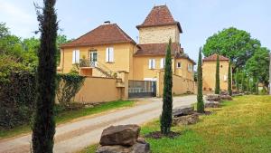 une grande maison jaune avec des arbres devant une route dans l'établissement Le domaine de l'Escadasse, à Faycelles