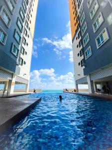 a person swimming in a swimming pool between two buildings at Harith sofea condo with pool in Kuala Terengganu