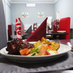 un piatto di alimenti con carne e verdure su un tavolo di Platinum Hotel a Gaborone