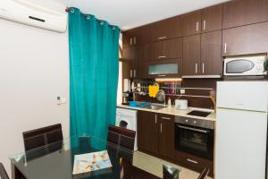 ソゾポルにあるGarden Beach Luxurios Apartment A9のキッチン(木製キャビネット、青いカーテン付)