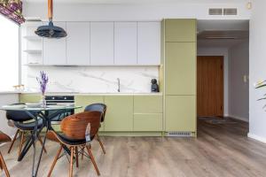 a kitchen with green and white cabinets and a table and chairs at Charming Apt with Spectacular Baltic Sea Views in Klaipėda