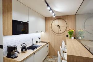 eine Küche mit weißen Schränken, einer Spüle und einer Uhr in der Unterkunft Kamilkowy Apartament in Karpacz