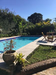 a swimming pool with a table and chairs next to it at Cantinho na Serra in Teresópolis