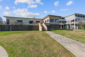 a building with a grassy yard in front of it at Bay Dreamer - Massive Bayfront Home with Private Pool home in Galveston