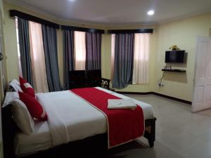 een slaapkamer met een bed met een rood-witte deken bij Bruton resorts in Kodaikānāl