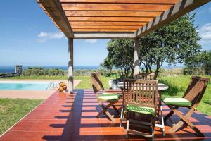 a wooden pergola with chairs and a table on a patio at Country House in Azores - S. Miguel in Ribeira Grande