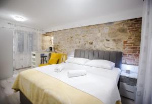 een slaapkamer met een groot wit bed met een bakstenen muur bij Lions luxury rooms in Split