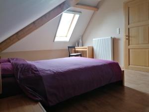 een slaapkamer met een paars bed en een raam bij L'Atelier d'Arthur - Gîte chaleureux avec jacuzzi. in Tenneville