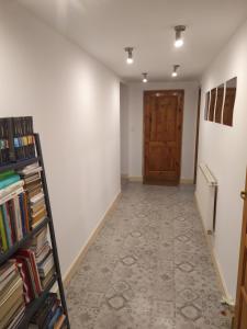 a hallway with a door and a shelf of books at Agroturystyka Klimaty- apartamenty nad rzeką in Międzylesie