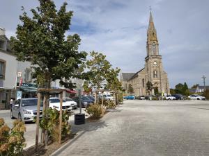 une église avec une tour d'horloge et un parking dans l'établissement Place d'Arradon, à Arradon