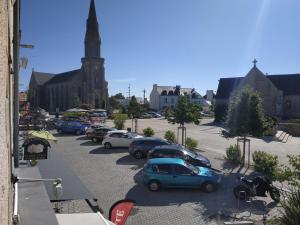 un groupe de voitures garées sur un parking en face d'une église dans l'établissement Place d'Arradon, à Arradon