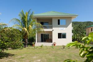 a house with a palm tree in front of it at Blue Sky Self Catering in Grand Anse