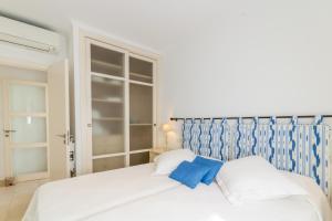 een wit bed met twee blauwe kussens in een slaapkamer bij Del mar 37 in Colonia de Sant Pere