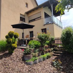 une maison avec un parasol et des plantes devant elle dans l'établissement Zum Buchenblick, à Saint-Wendel