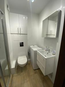 een witte badkamer met een toilet en een wastafel bij Kilińskiego 35 in Ełk