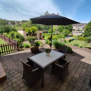 - une table et des chaises avec un parasol sur la terrasse dans l'établissement Zum Buchenblick, à Saint-Wendel